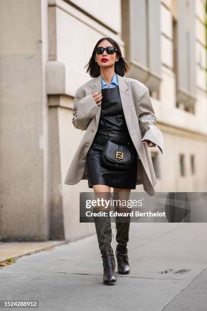 Heart Evangelista wears black sunglasses from Saint Laurent, diamond earrings, a pale blue shirt from Fendi, a black shiny leather tank-top / short...