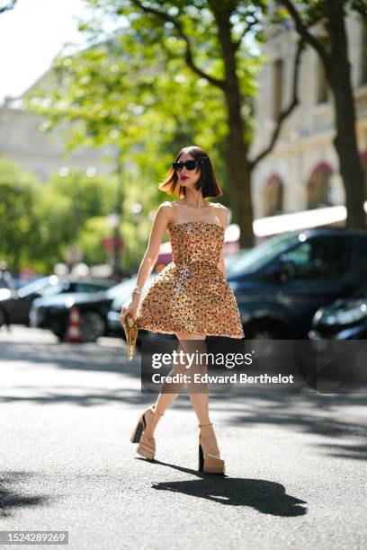 Heart Evangelista wears black cat eyes sunglasses from Saint Laurent, a beige brown with embroidered brown / green / silver sequined shoulder-off /...