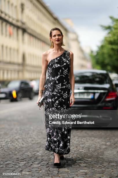 Helena Bordon wears gold earrings, a black with white embroidered sequined flower pattern / asymmetric shoulder / long dress, yellow and white gold...