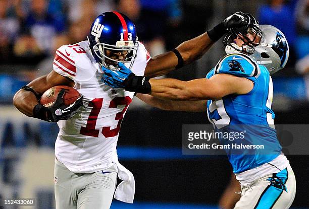 Ramses Barden of the New York Giants stiff-arms Luke Kuechly of the Carolina Panthers during play at Bank of America Stadium on September 20, 2012 in...