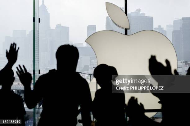 Customer is greeted by Apple employees as she enters the Hong Kong Apple store to get an iPhone 5 on September 21, 2012. Apple's iPhone 5 hit stores...