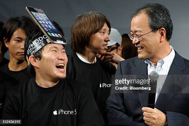 Takashi Tanaka, president of KDDI Corp., right, speaks with a customer during a launch event for the Apple Inc. IPhone 5 in Tokyo, Japan, on Friday,...