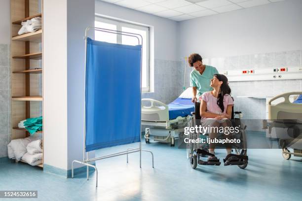 woman in wheelchair with nurse in hospital - patient in hospital stock pictures, royalty-free photos & images