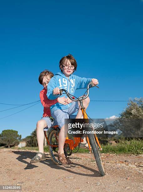 two boys with glasses riding a old bike