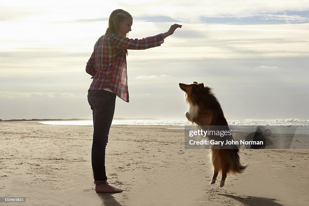 Girl ( 14-16) training dog on beach