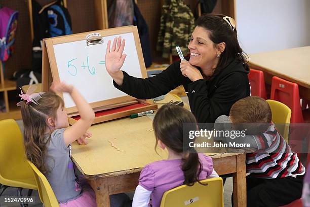 Teacher Denise Severing congratulates a child during a math lesson at the federally-funded Head Start school on September 20, 2012 in Woodbourne, New...