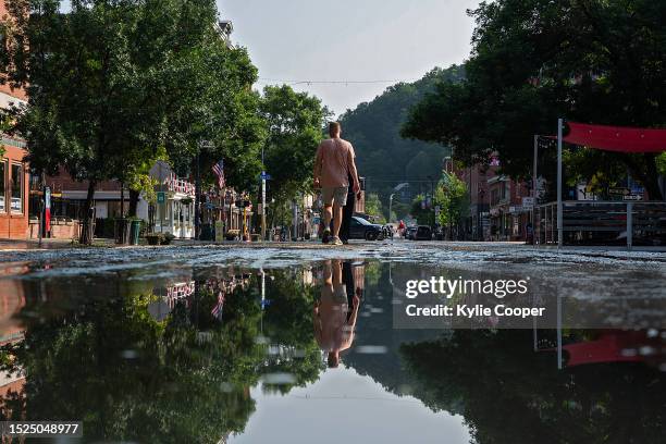 Residents walk along a muddy Main Street after flood waters receded on July 11, 2023 in Montpelier, Vermont. Up to eight inches of rain fell over 48...