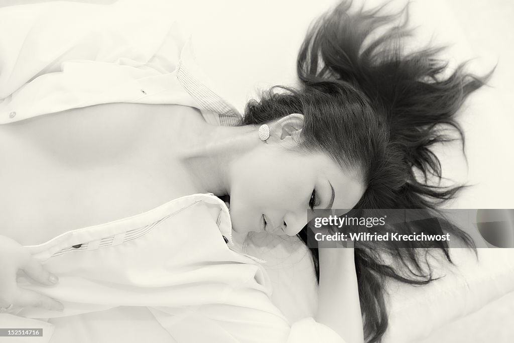 A woman with an open shirt lying on a bed