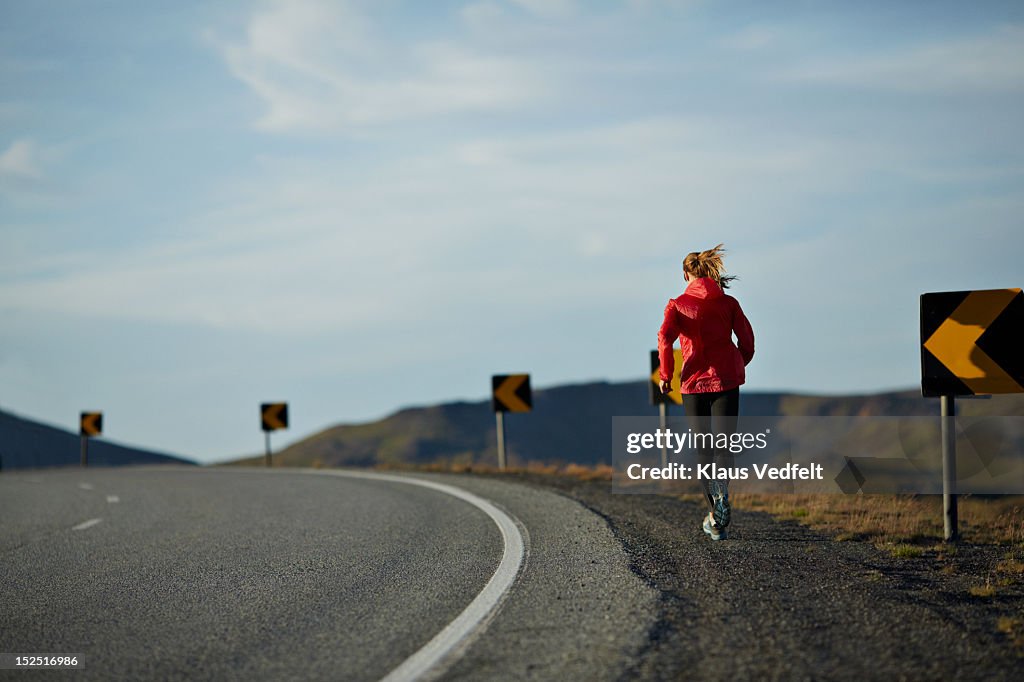 Woman running uphill on big road,mountains in back