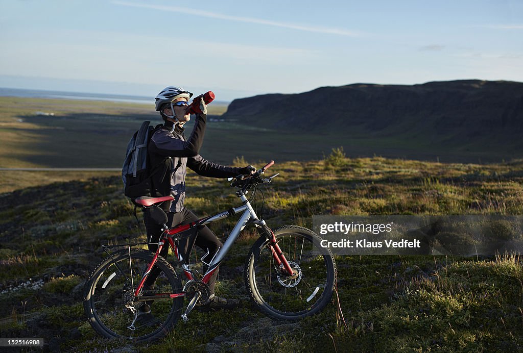 Mountainbiker taking a drinking brake on the hill