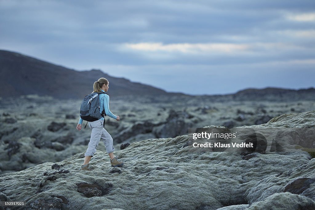 Woman with backpack walking threw lava landscape