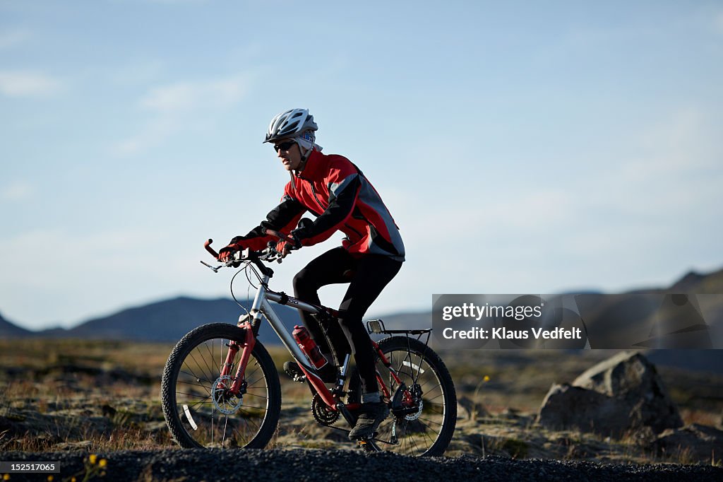 Man on mountainbike cycling up hill off-road