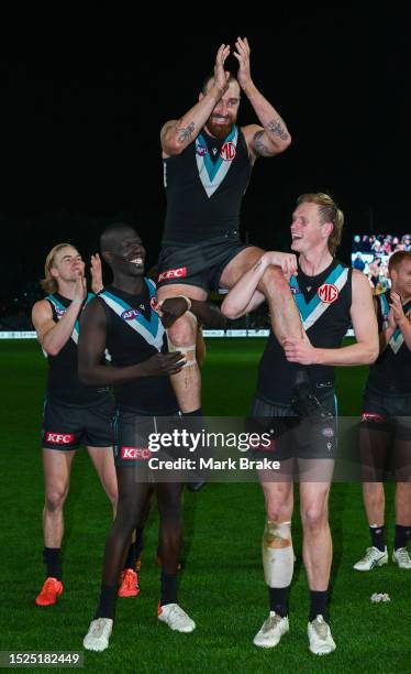 Charlie Dixon of Port Adelaide is carried off the ground by Aliir Aliir and Sam Hayes for his 200th and during the round 17 AFL match between Port...