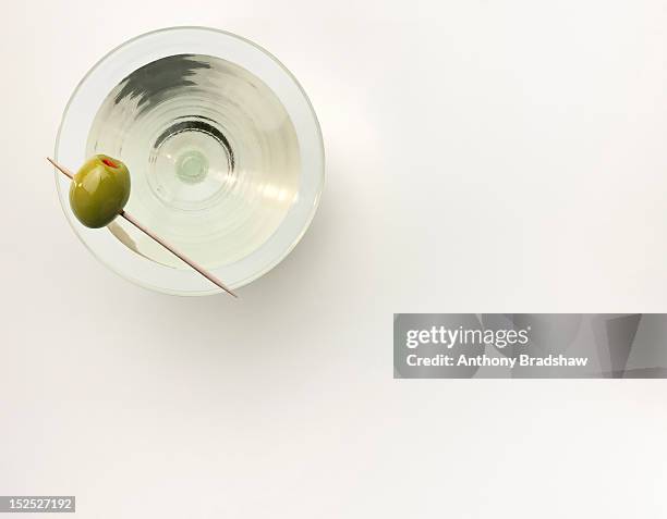 a martini served with a stuffed olive - martini glass stock-fotos und bilder