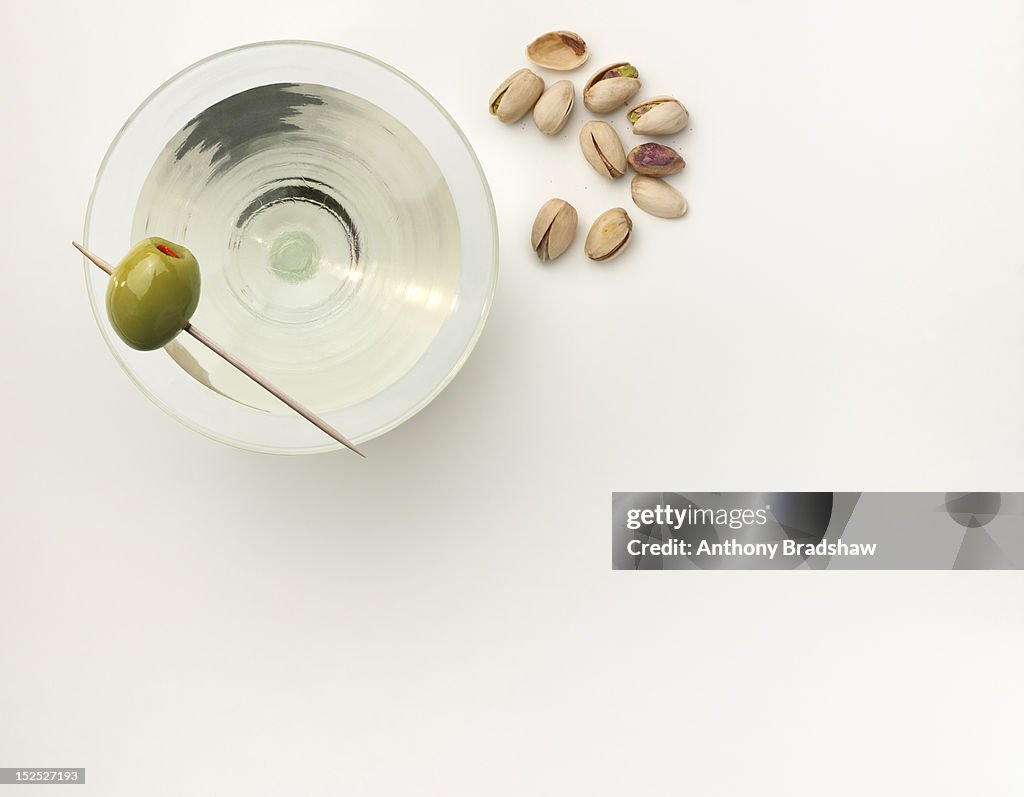 A martini with a stuffed olive and pistachio nuts