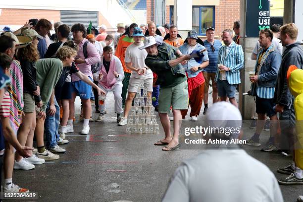 General view as spectators play a game of cricket under a Stand, using a umbrella as a bat and plastic cups for stumps, during the rain delay prior...