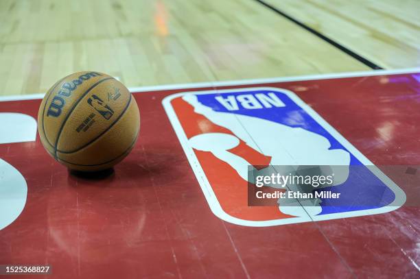 Basketball is placed on the court next to an NBA logo during a break in the first half of a 2023 NBA Summer League game between the Portland Trail...