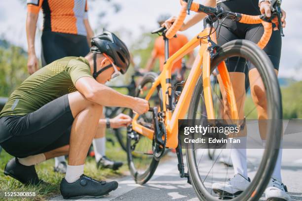 asian chinese cyclist helping his team checking on bicycle chain at roadside in rural scene weekend morning - triathlon gear stock pictures, royalty-free photos & images