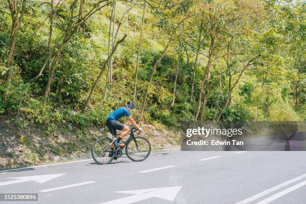 ciclista chinês asiático olhando por cima do ombro esperando por seu companheiro de equipe na beira da estrada rural - líder da corrida atleta - fotografias e filmes do acervo