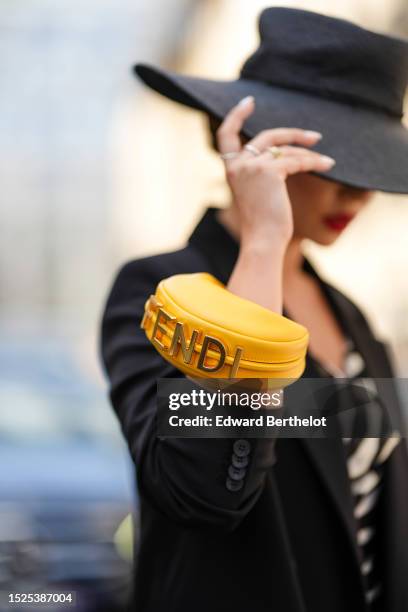 Merve Gorgotz wears a black braided wicker large hat, gold large cut-out FF logo pendant earrings, a black and white zebra print pattern V-neck /...