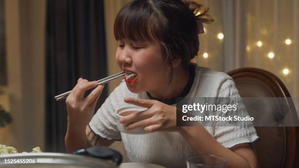closeup group of happy asian friends eating hot pot meal while gathering together for chinese new year reunion meal at home in evening. lifestyle enjoy food. - nabe stock pictures, royalty-free photos & images