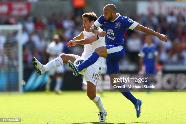 Danny Graham of Swansea City is challenged by John Heitinga of Everton during the Barclays Premier League match between Swansea City and Everton at...