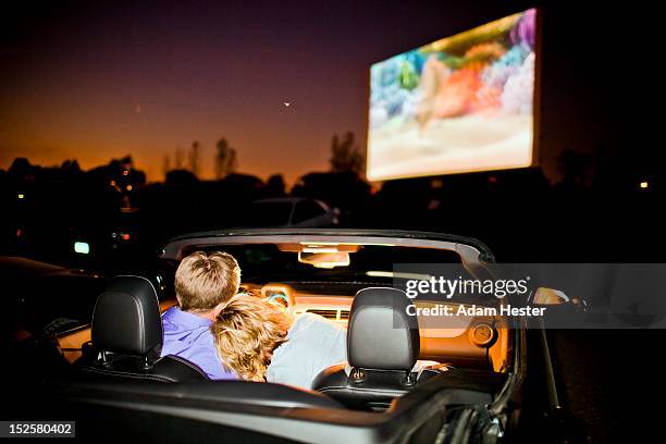 a couple having fun in their car at a theater. - drive in movie theater stock pictures, royalty-free photos & images