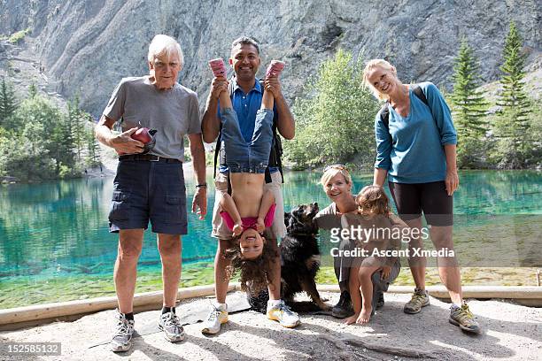 extended family with dog pause beside mtn lake - family dog stock-fotos und bilder
