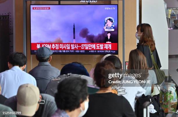 People watch a television screen showing a news broadcast with file footage of a North Korean missile test, at a railway station in Seoul on July 12,...