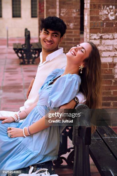 teenagers boyfriend and girlfriend, together on a street bench, laugh in fun - girl dress romantic stock-fotos und bilder