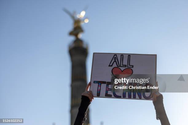 Woman holds sign that reads All love Techno in front of Victory Column as techno music enthusiasts dance during the Rave the Planet parade in...