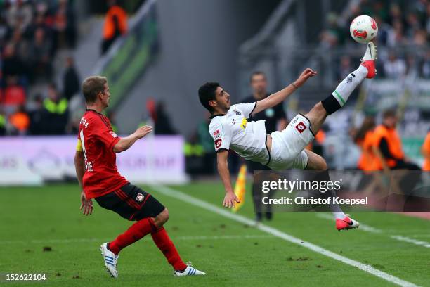 Tolga Cigerci of Moenchengladbach plays an overhead kick and Lars Bender of Leverkusen watches him during the Bundesliga match between Bayer 04...