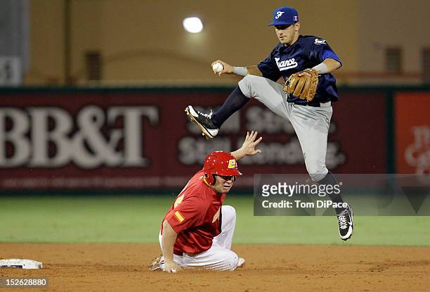 Maxime Lefevre of Team France jumps to avoid a sliding Rafael Alvarez of Team Spain during game 2 of the Qualifying Round of the 2013 World Baseball...