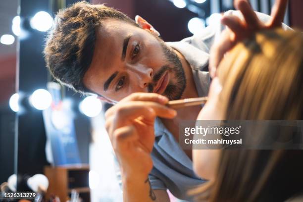 makeup artist working applying the eyeshadow - geschminkt gezicht stockfoto's en -beelden