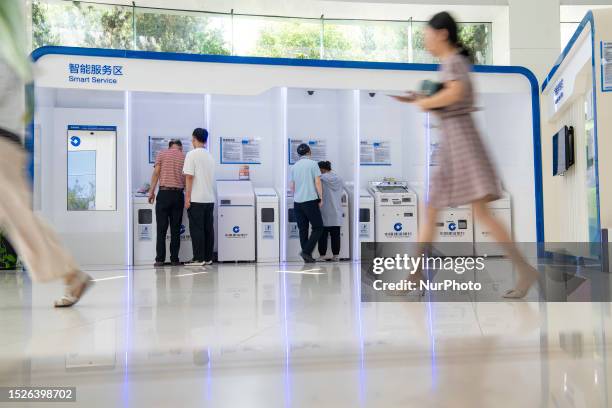 Customers handle business at a smart service area of a bank in Hai 'an, East China's Jiangsu province, July 12, 2023. The People's Bank of China...