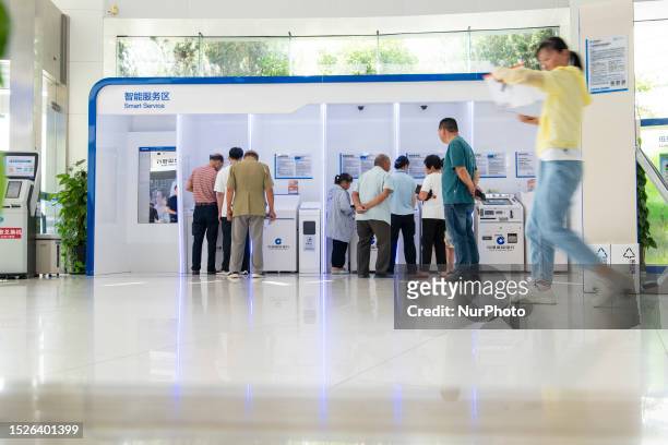 Customers handle business at a smart service area of a bank in Hai 'an, East China's Jiangsu province, July 12, 2023. The People's Bank of China...