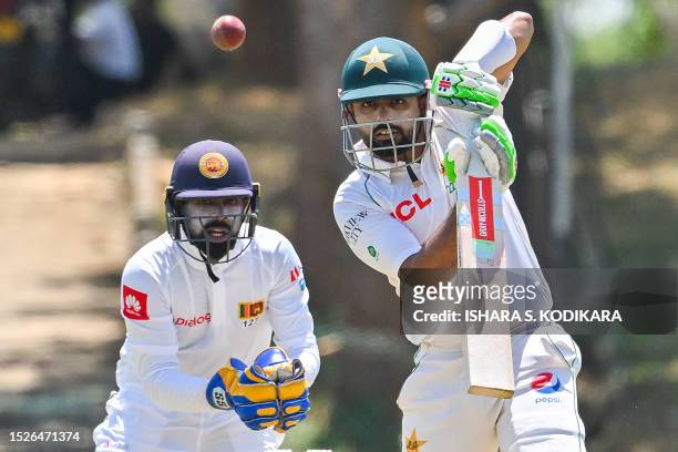 Pakistan's captain Babar Azam plays a shot as Sri Lanka Cricket President's XI wicketkeeper Niroshan Dickwella watches during the second day of the...