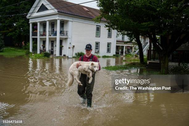 Tyler Jovic, of Montpelier, carries his neighbor's dog to dry ground on Tuesday afternoon, July 11, 2023. Vermont has been under a State of Emergency...