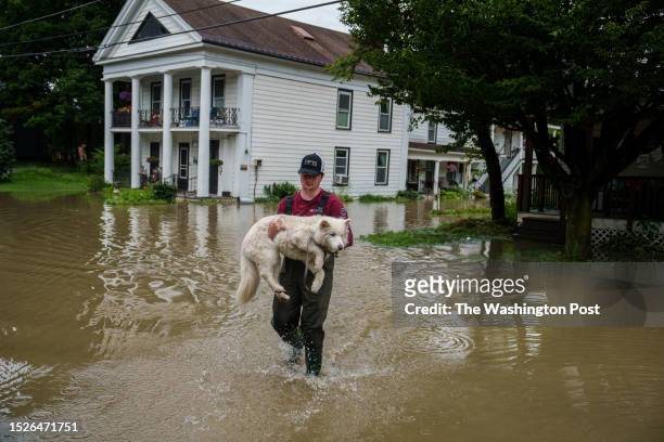 Tyler Jovic, of Montpelier, carries his neighbor's dog to dry ground on Tuesday afternoon, July 11, 2023. Vermont has been under a State of Emergency...