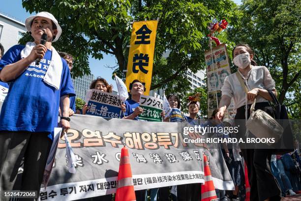 Pedestrian walks past a group of protesters, including South Korean activists, taking part in a rally to protest against the Japanese government's...