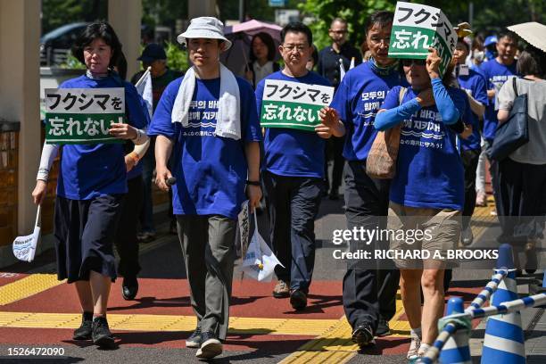 Protesters, including South Korean activists, hold signs stating Fukushima and take part in a rally during a protest against the Japanese...