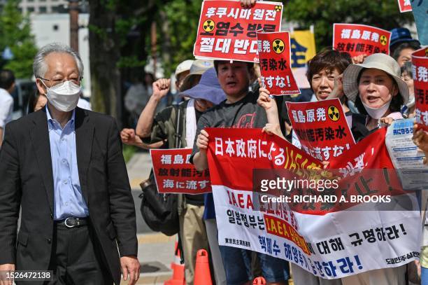 Man walks past as protesters, including South Korean activists, take part in a rally to protest against the Japanese government's plan to release...