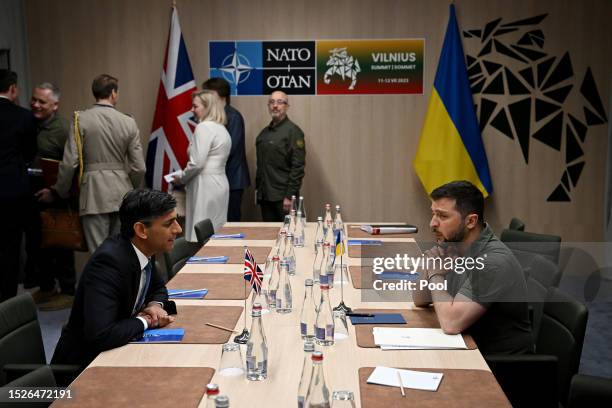 Ukrainian President Volodymyr Zelensky speaks with Britain's Prime Minister Rishi Sunak during a bilateral meeting on the sidelines of the NATO...