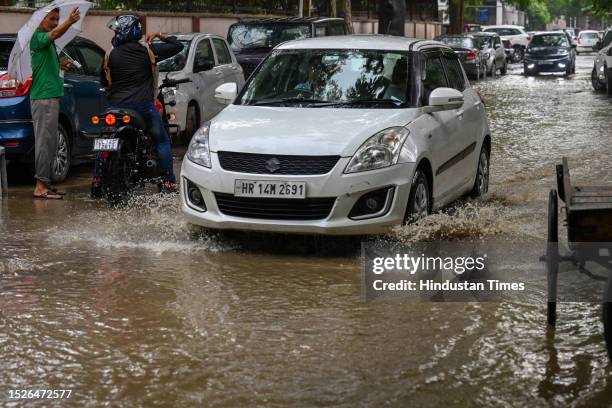 Commuters moves through a water logged street after heavy rains lashes out the city at ITO kabristan Lane on July 10, 2023 in New Delhi, India....