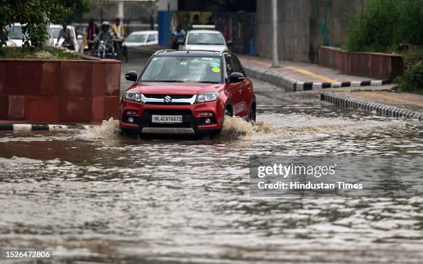 Commuters moves through a water logged street after heavy rains lashes out the city at Pragati maiden ring road on July 10, 2023 in New Delhi, India....