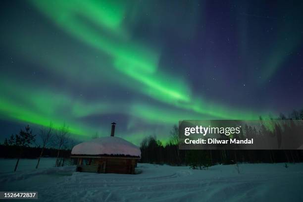 enchanting dance of the northern lights over a cabin in luosto, lapland - northern lights michigan bildbanksfoton och bilder