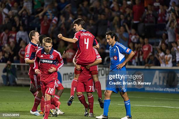 Alex of Chicago Fire picks up teammate Alvaro Fernandez after Fernandez's goal as Alessandro Nesta of Montreal Impact stands on the field at Toyota...