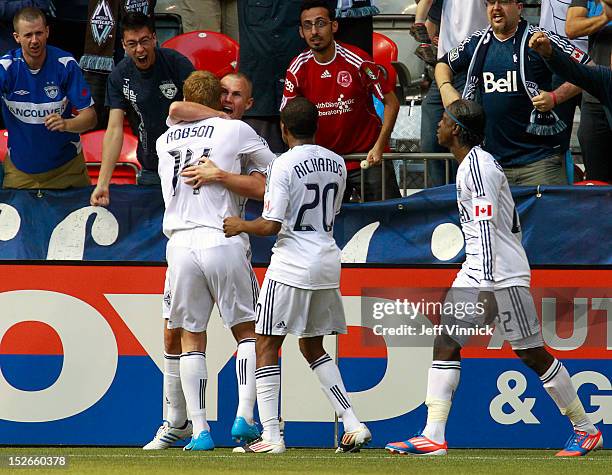 Barry Robson of the Vancouver Whitecaps FC hugs goal scorer Kenny Miller \while Dane Richards and Darren Mattocks approach against the Colorado...