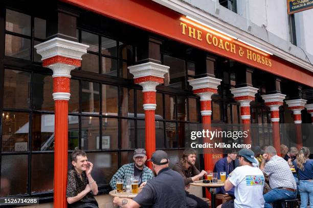 People outside enjoying a Summer afternoon drink at The Coach & Horses pub on the corner of Greek Street and Romilly Street in Soho on 9th July 2023...