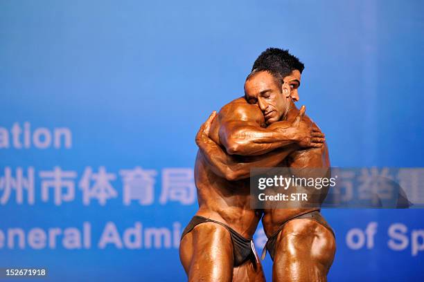 This picture taken on September 23 shows two competitors hugging each other during the 46th Asian Bodybuilding and Physique Sports Championships in...